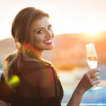 Girl holding a glass of Champagne looking into sunset