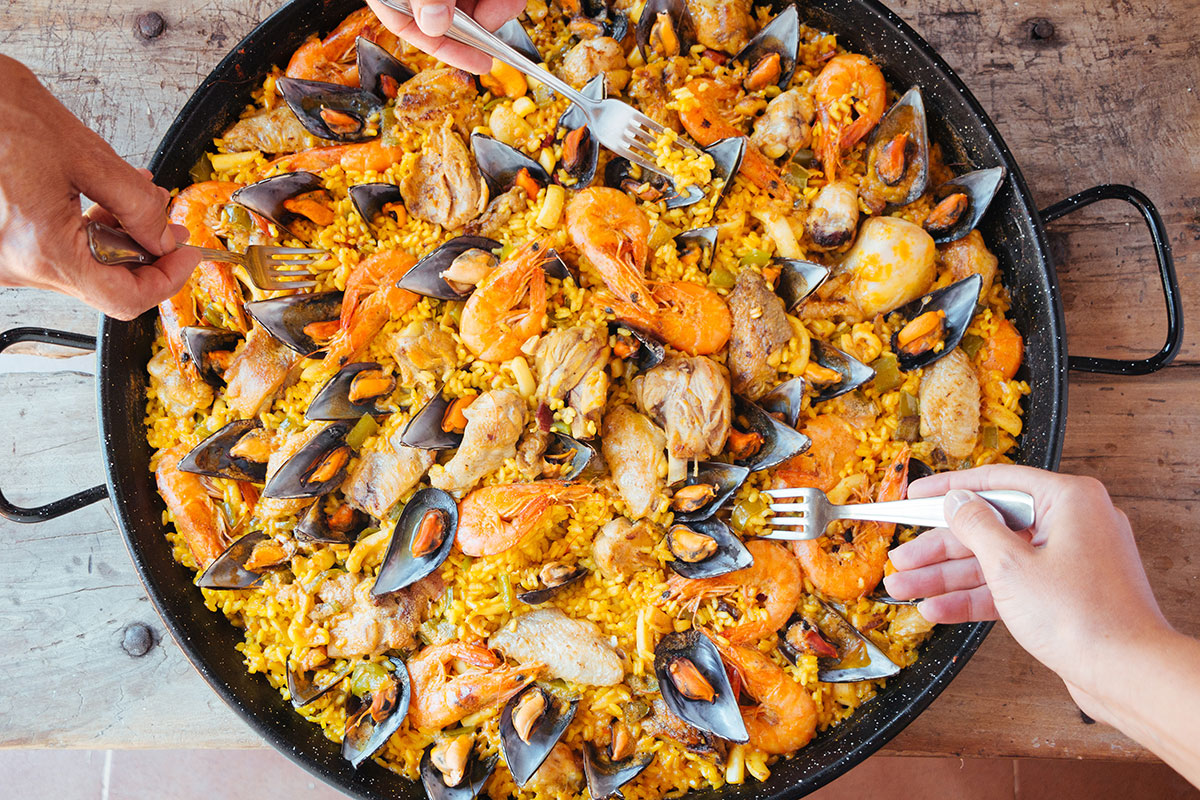 Pan of tasty paella being eaten with forks