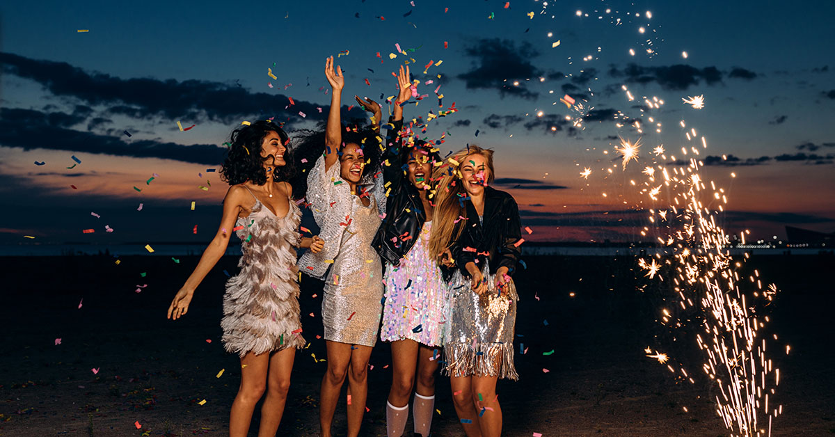 four girls on the beach at night with sparks flying