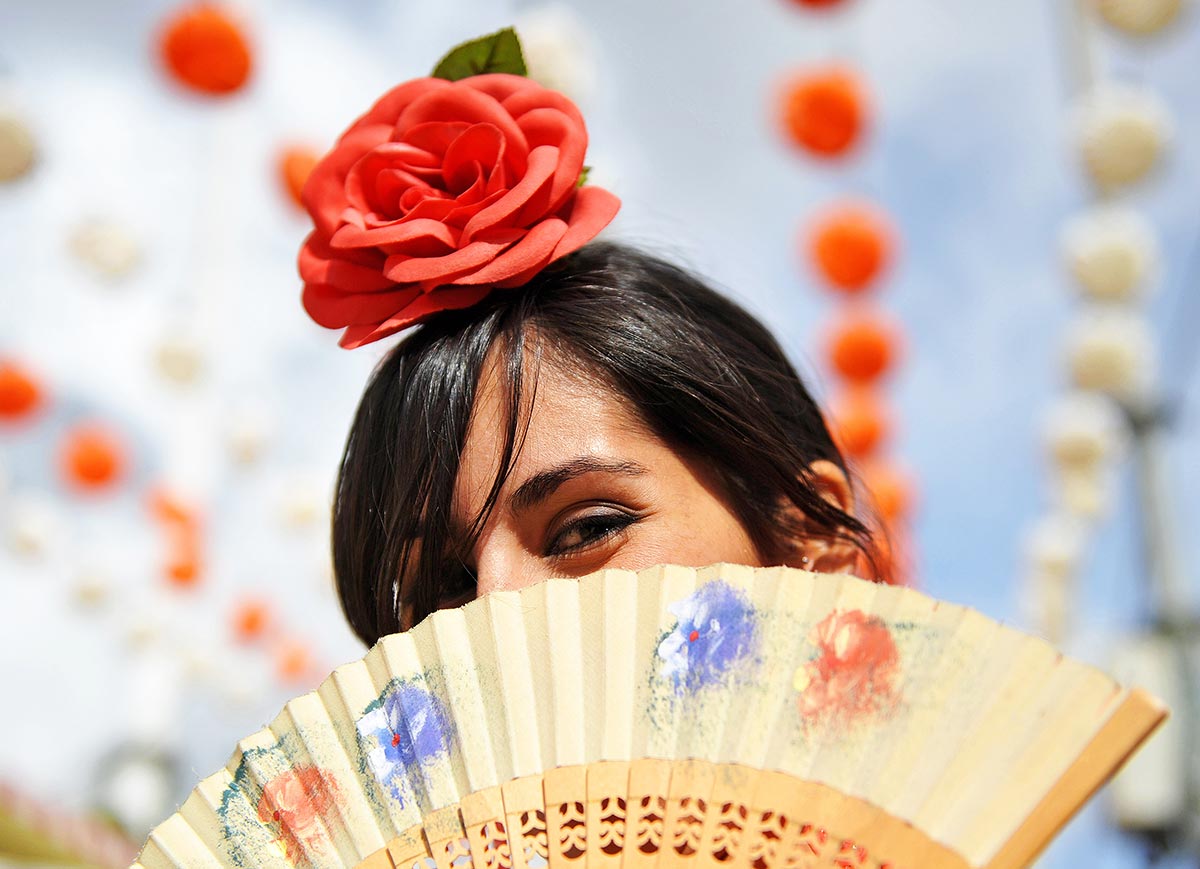 Girl at the feria looking over a fan