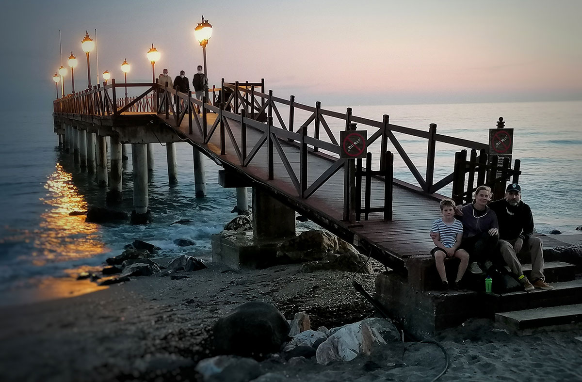 Family sitting on the Marbella Club pier on evening.