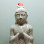 Ceramic Buddha praying with father christmas hat.