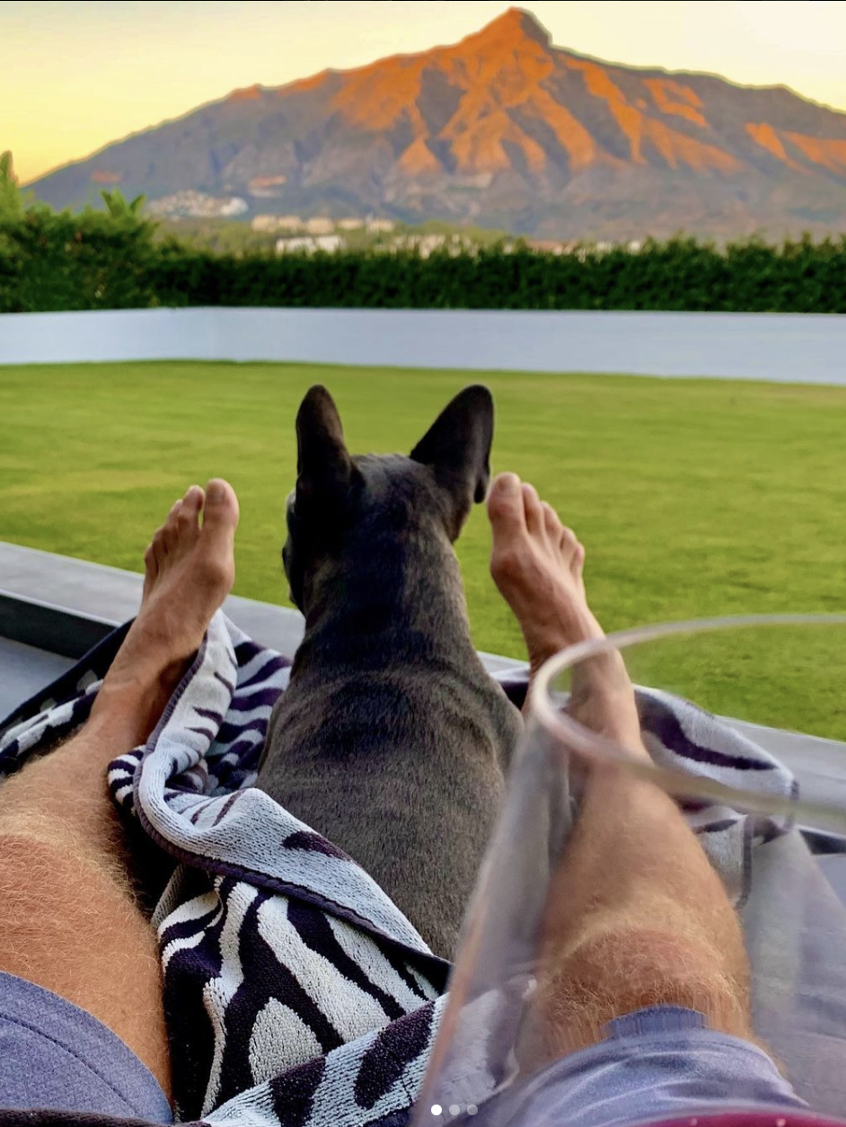 Legs, dog and view of Marbella's Concha mountain at sunset.