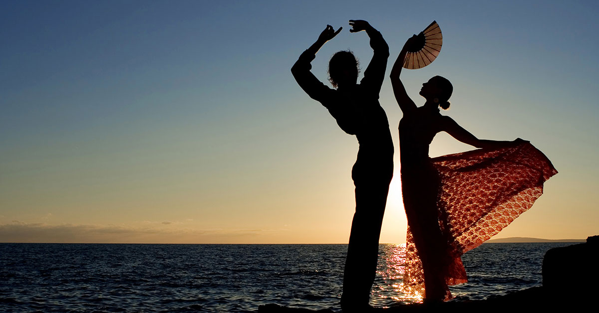 Flamenco dancer couple in silhouette against sea and sunset.