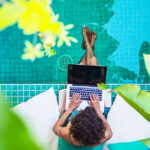Lady on Laptop sitting on edge of swimming pool