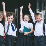 Four Happy children raising hands at school