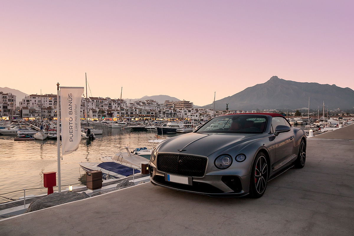 Luxury car parked on the quay at Puerto Banus at sunset.