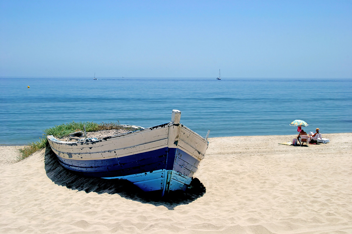 Old wooden boat on beach in Marbella