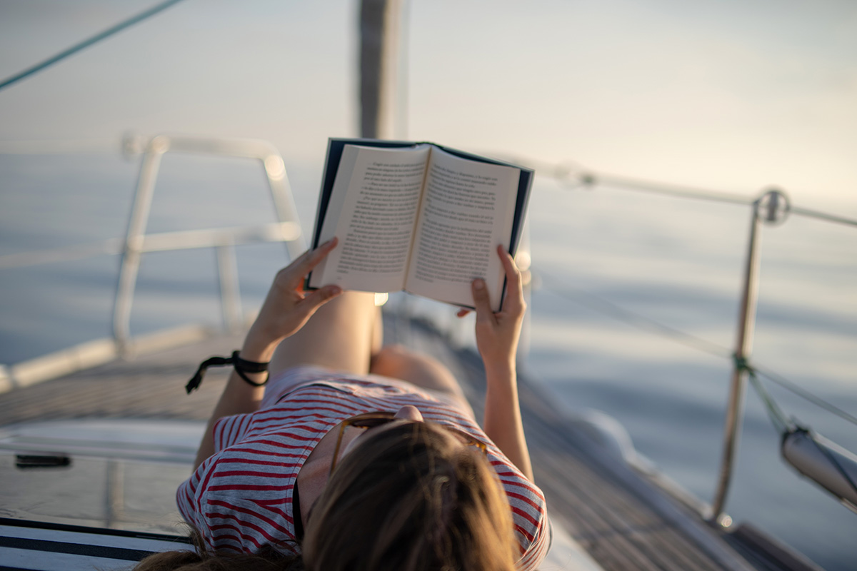 Girl lying on a yacht and reading a book