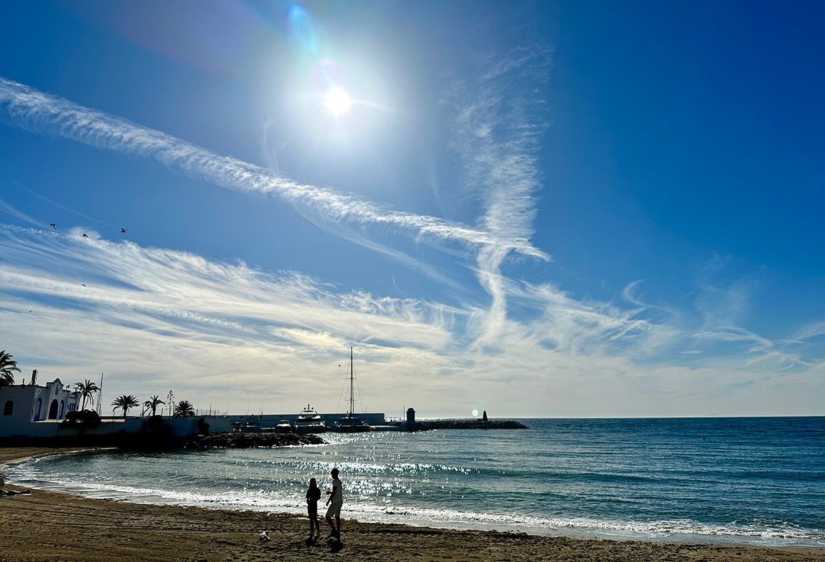 Marbella baeacfront, early morning and light clouds and aeroplane trails on the horizon.